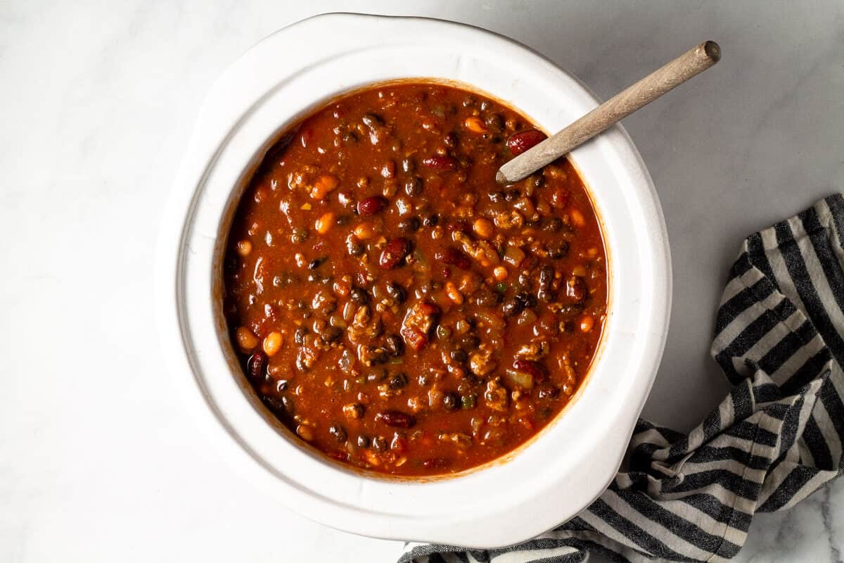 Overhead shot of a white crock pot filled with slow cooker turkey chili
