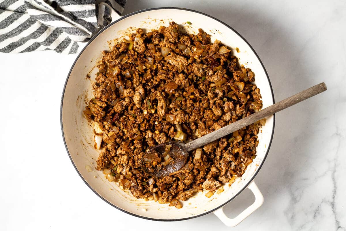 Overhead shot of a white pan filled with ground turkey and chili spices