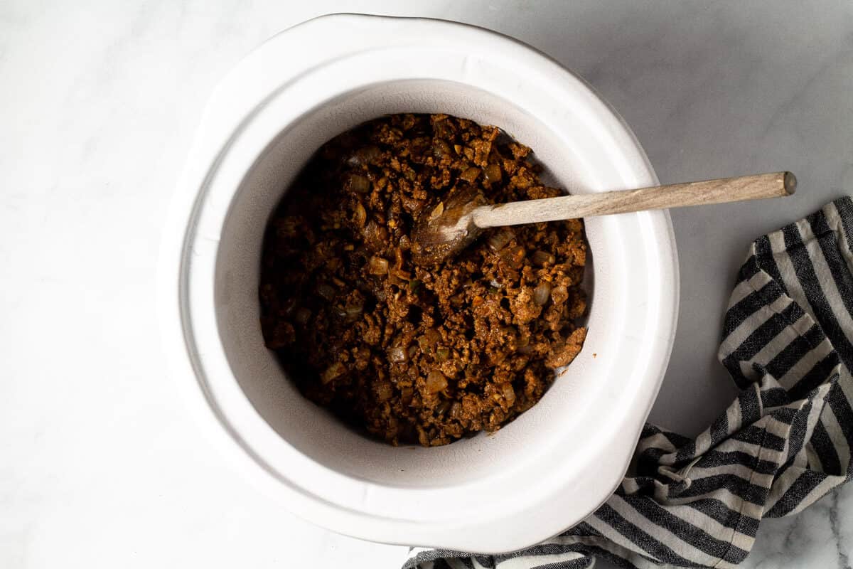 A white crock pot insert filled with ground turkey
