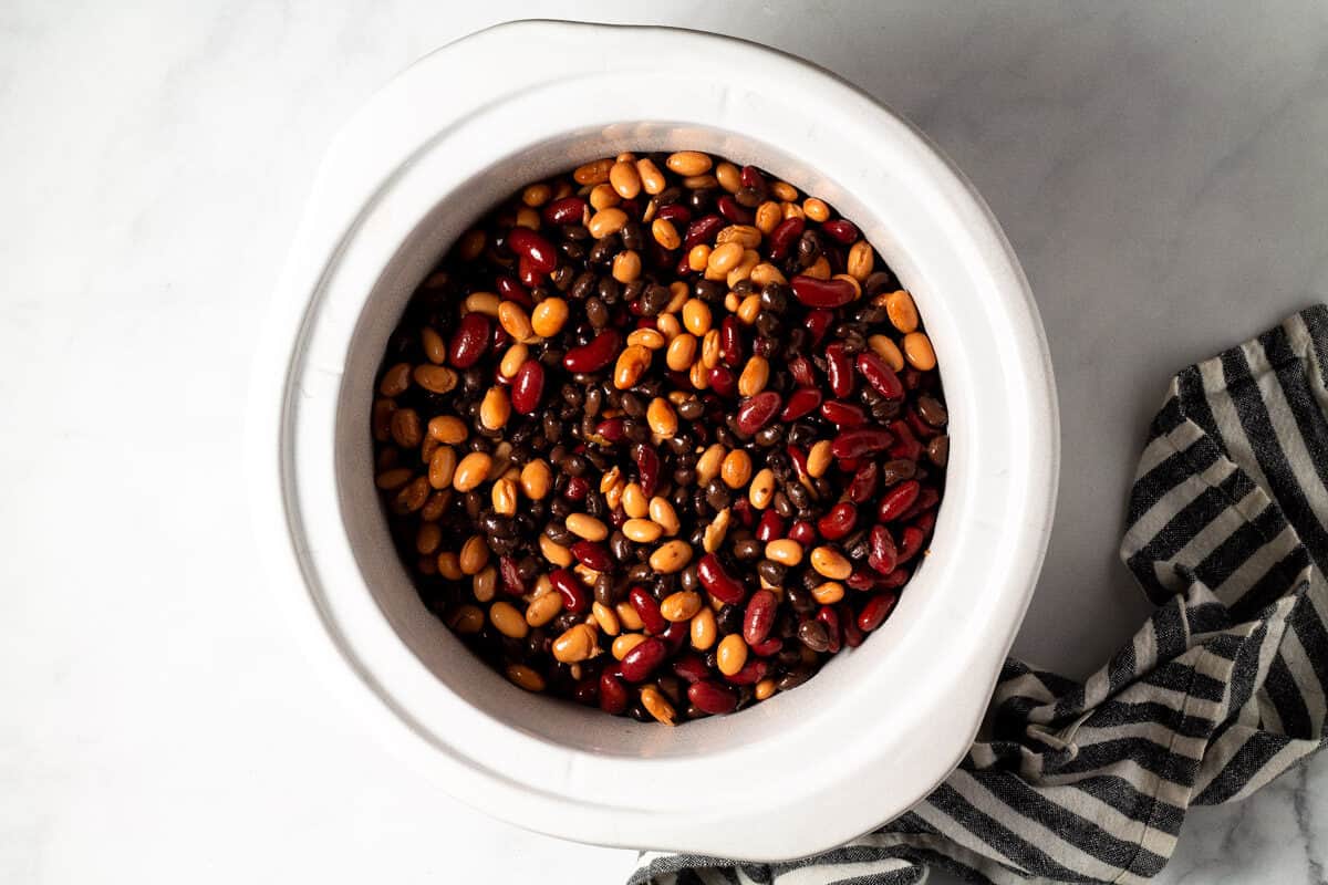 A white crock pot insert filled with beans
