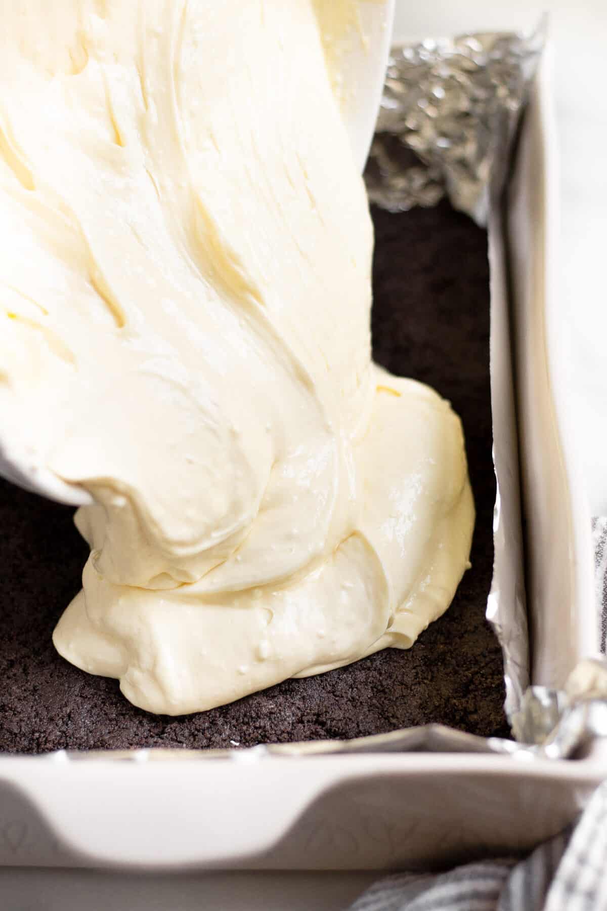 Cheesecake batter being poured onto an oreo crust