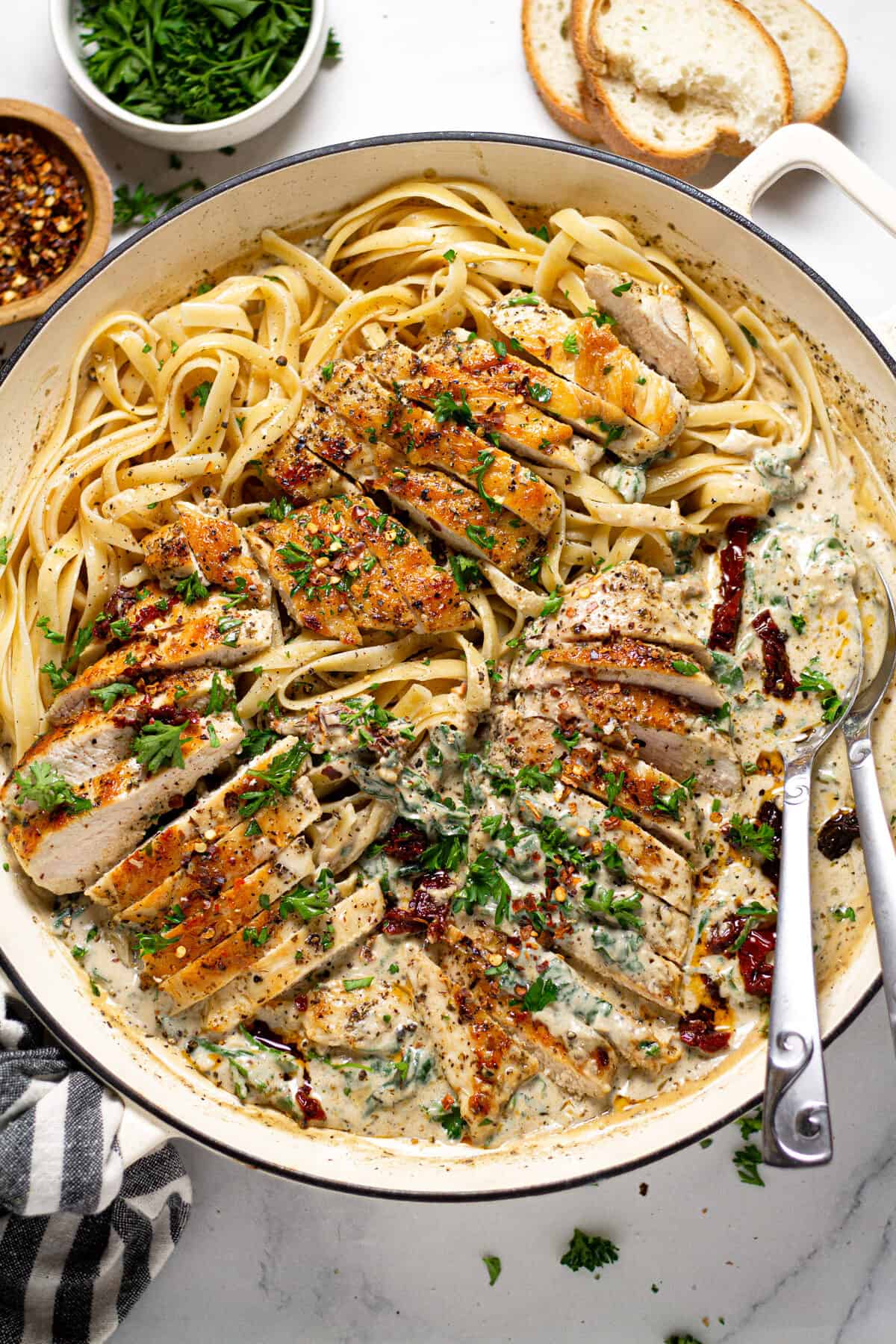 Overhead shot of a pan filled with creamy Tuscan chicken over fettuccine noodles