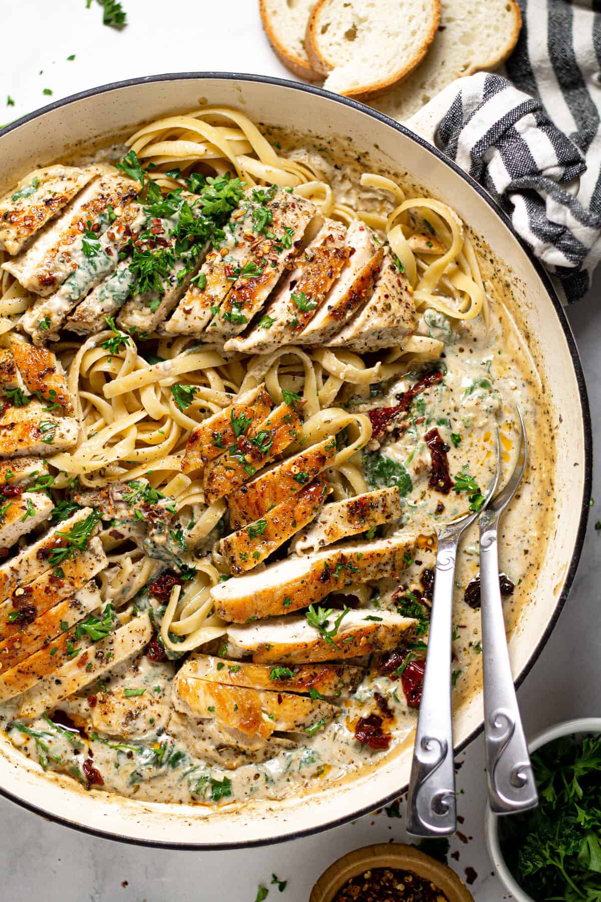 Overhead shot of a pan filled with creamy Tuscan chicken over fettuccine noodles