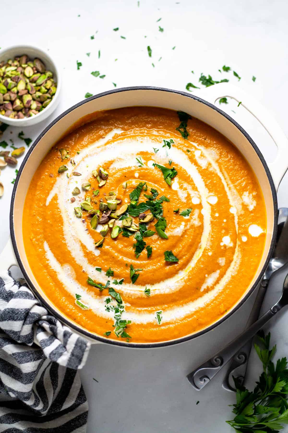 Overhead shot of a white pot filled with creamy vegan carrot soup 