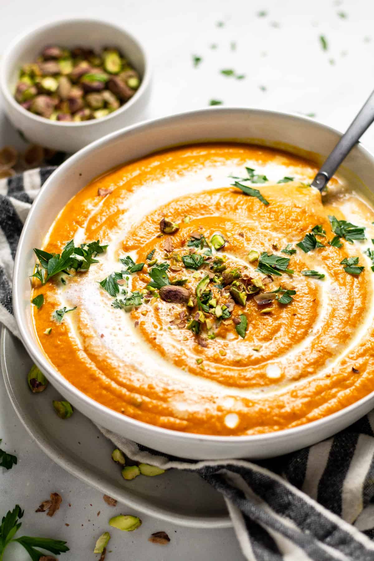 Close up shot of a white bowl filled with creamy vegan carrot soup 