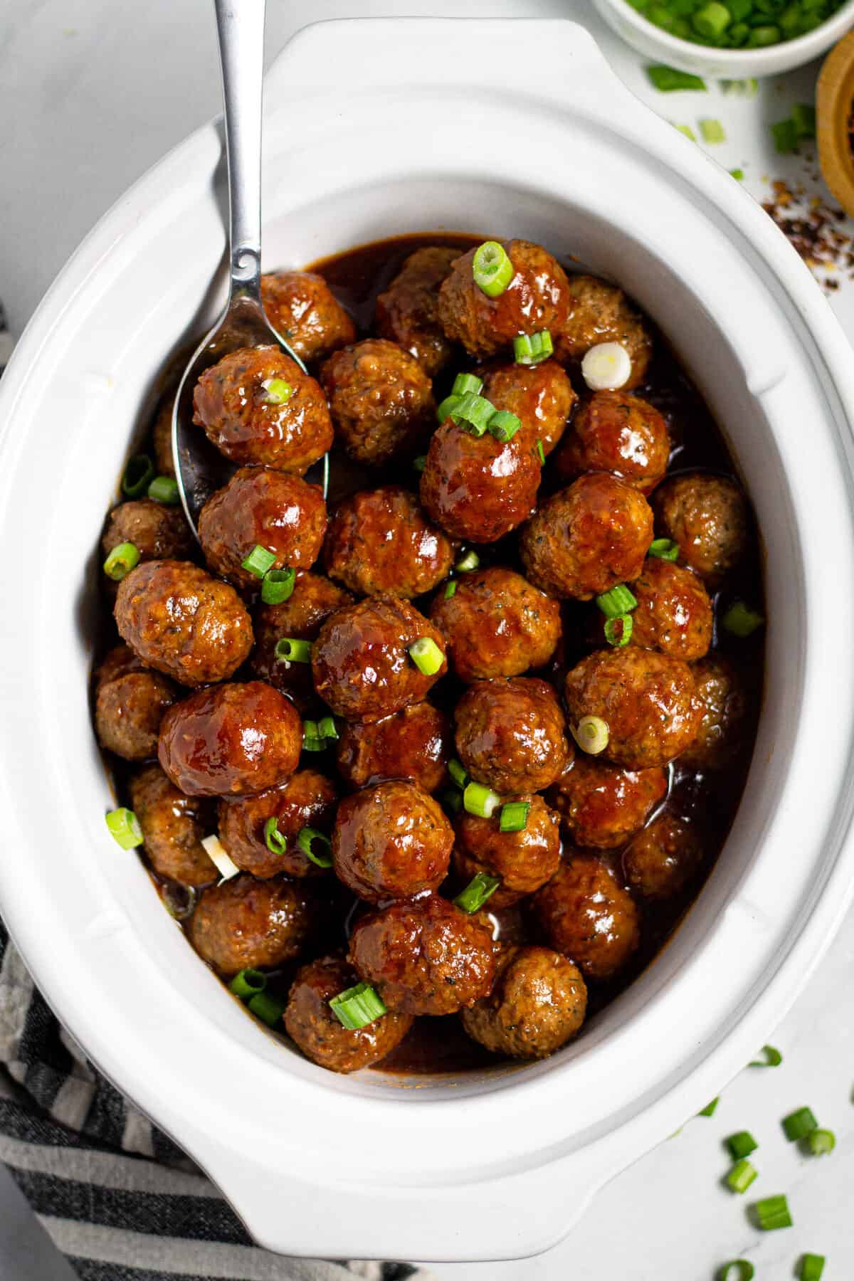 Overhead shot of a white crock pot insert filled with bourbon whiskey meatballs