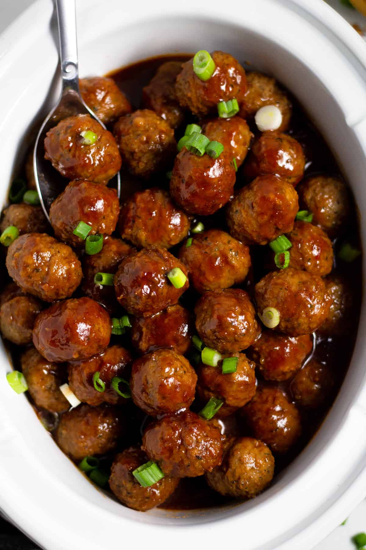 Overhead shot of a white crock pot insert filled with bourbon whiskey meatballs