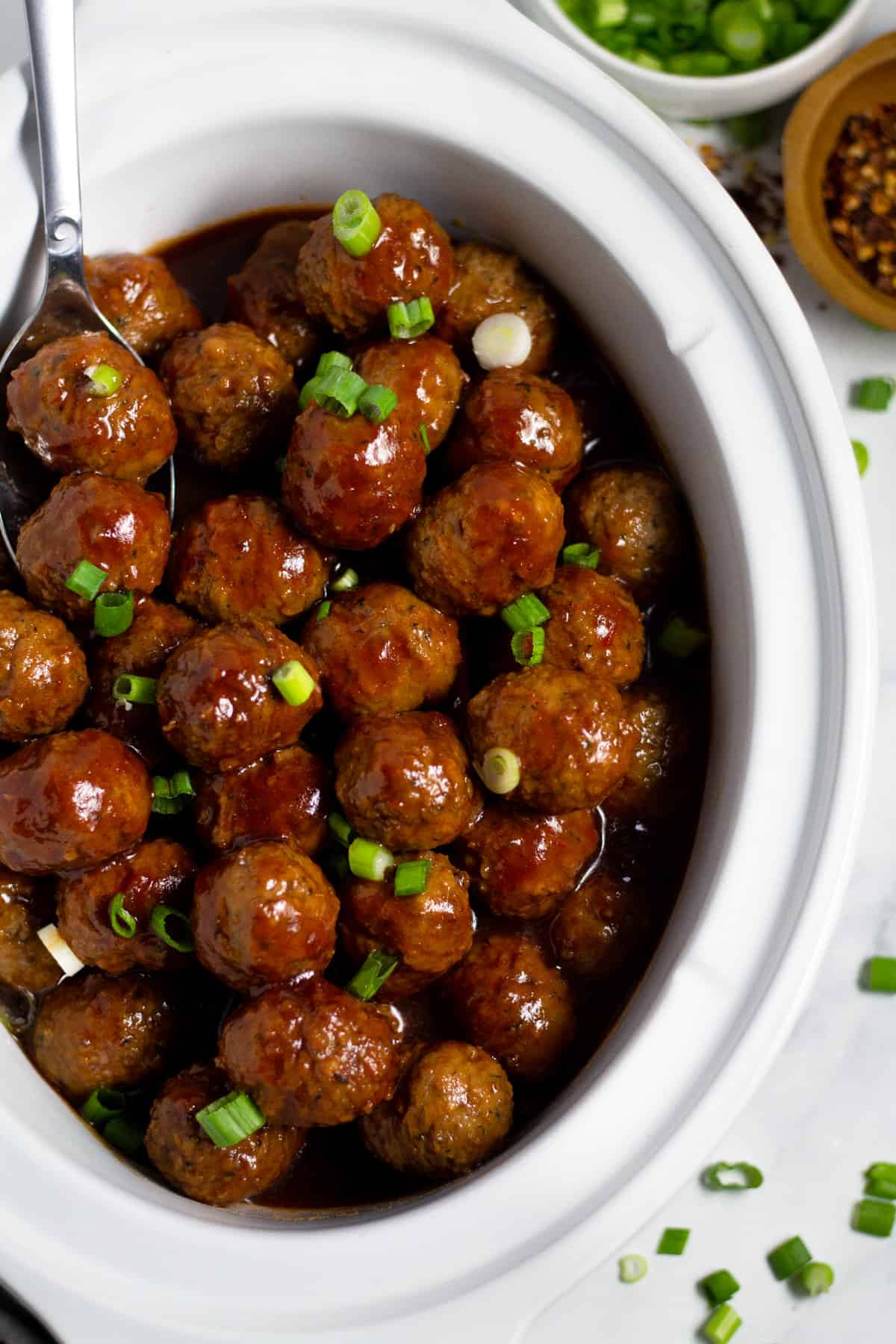 Overhead shot of a white crock pot insert filled with bourbon whiskey meatballs