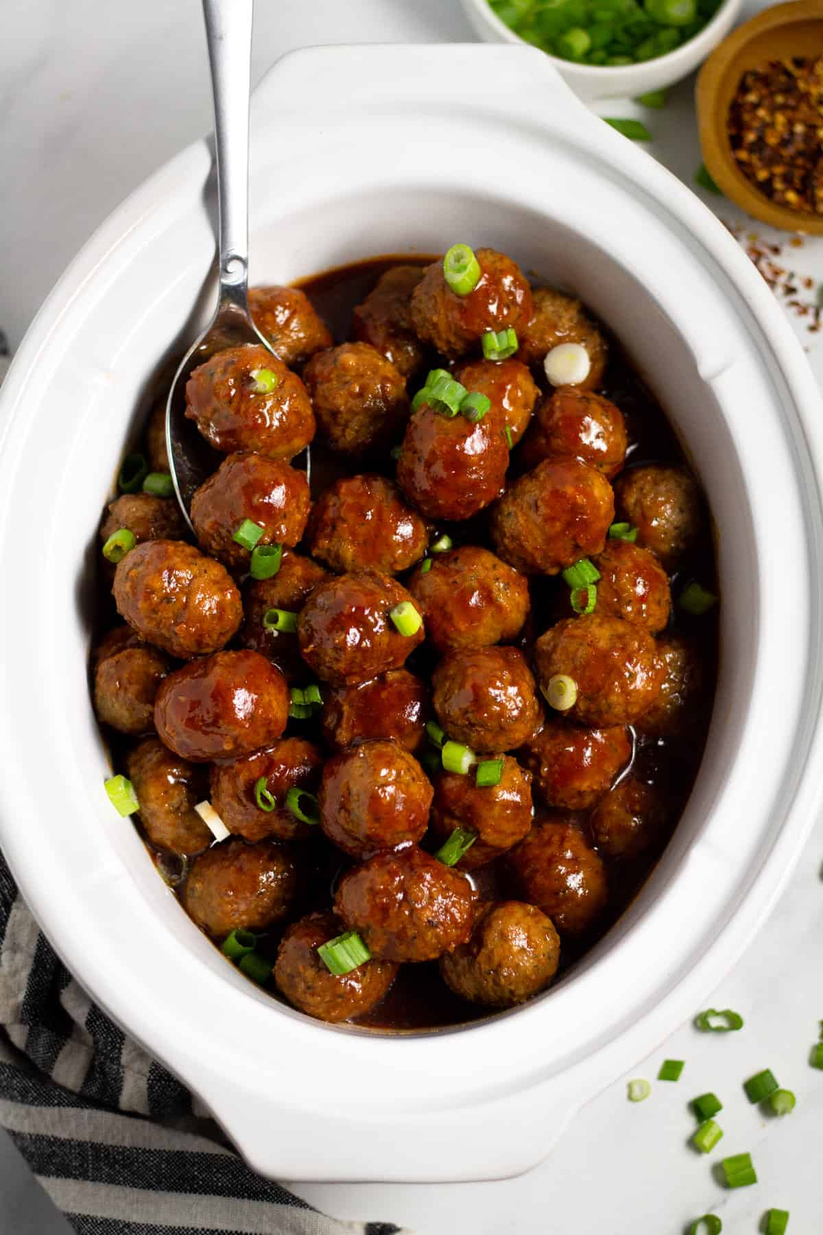 Overhead shot of a white crock pot insert filled with bourbon whiskey meatballs