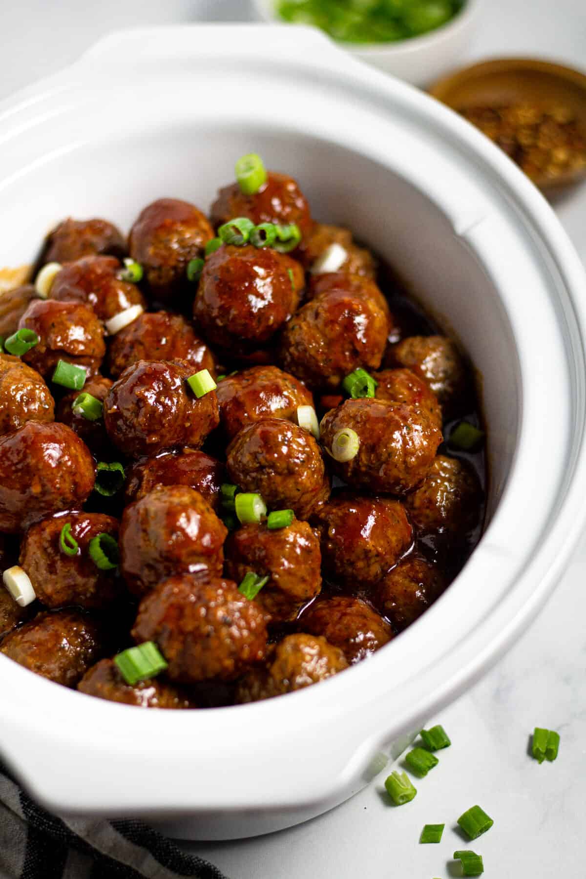 Close up shot of a white crock pot insert filled with bourbon whiskey meatballs