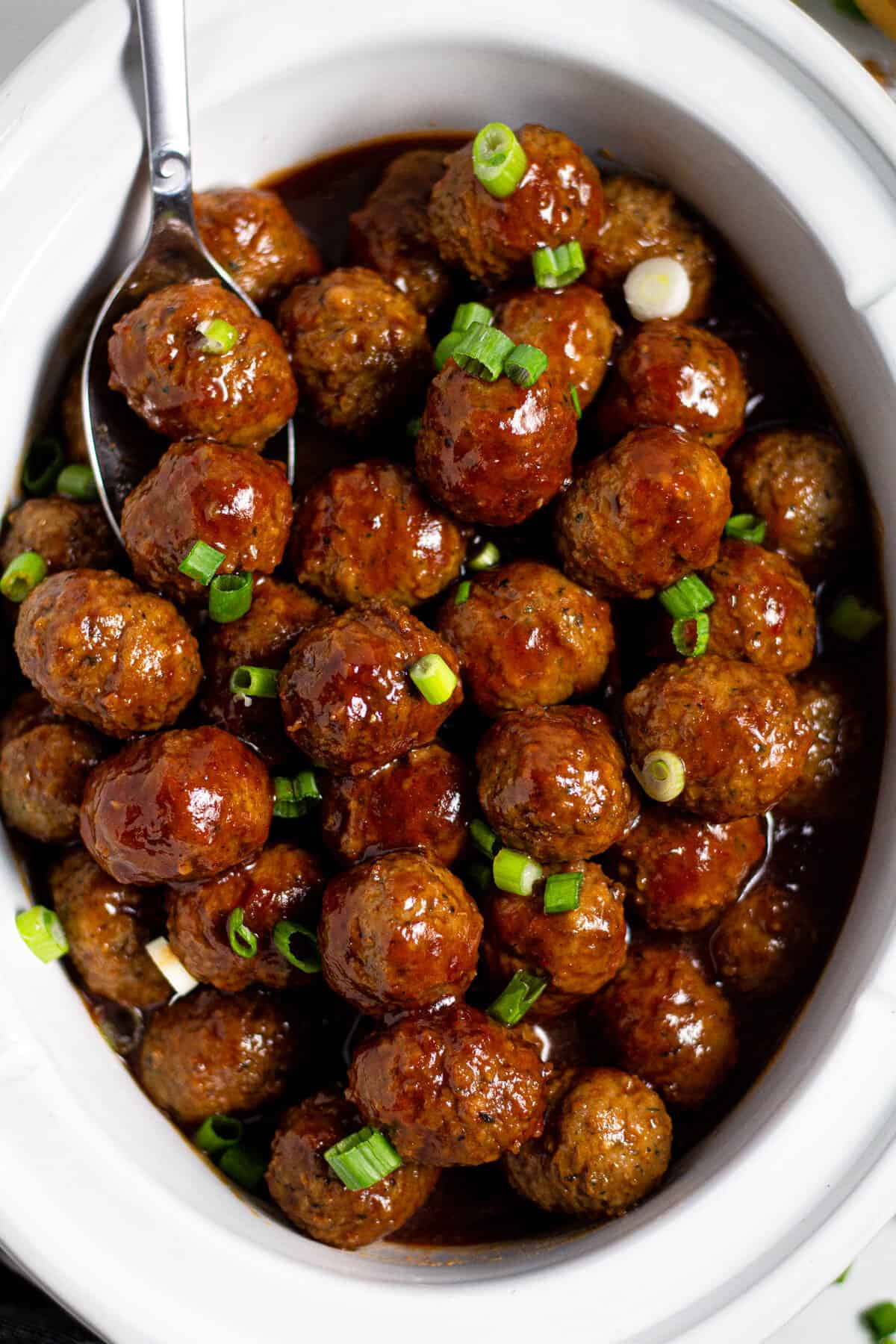 Overhead shot of a white crock pot insert filled with bourbon whiskey meatballs