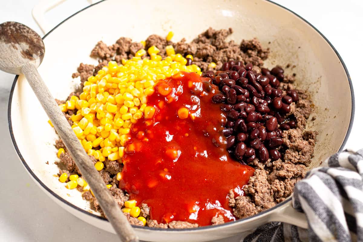 Large saute pan filled with cooked ground beef corn black beans and taco sauce