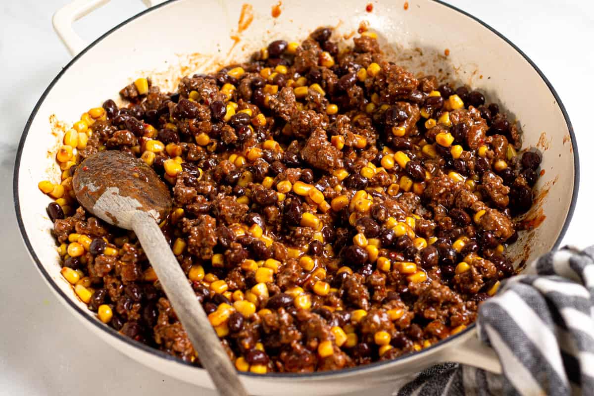 Large saute pan filled with cooked ground beef filling for chimichangas
