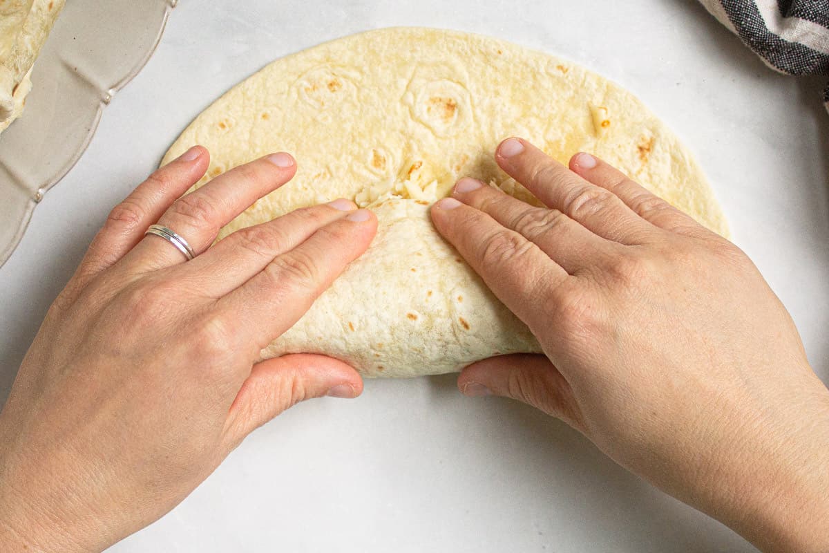 A flour tortilla being rolled into a chimichanga