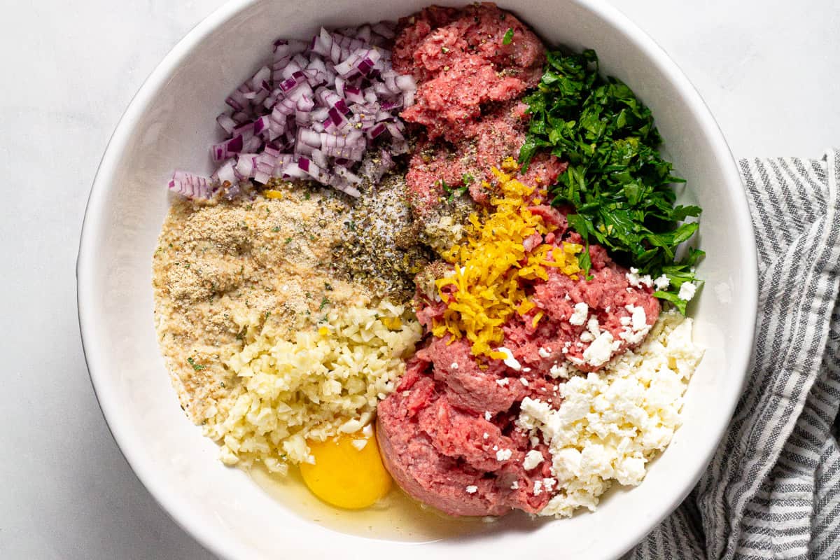 Large white bowl with ingredients to make Greek meatballs