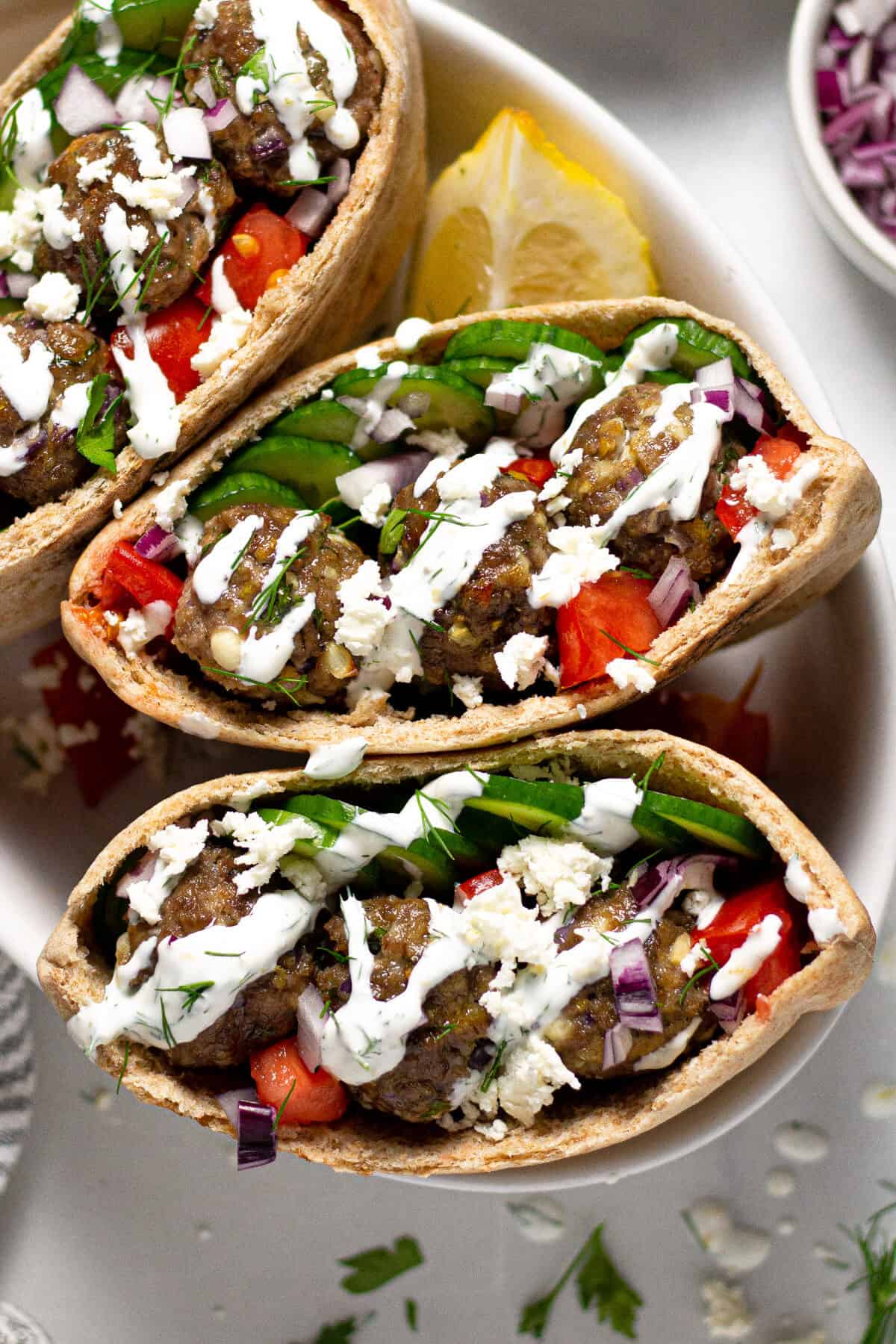 Overhead shot of three Greek meatball gyros with yogurt sauce and fresh dill