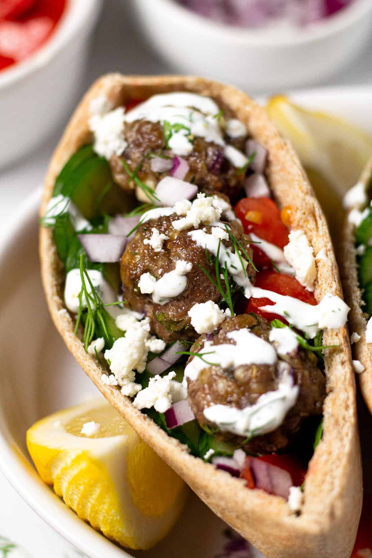 Close up shot of a Greek meatball gyro with yogurt sauce and fresh dill