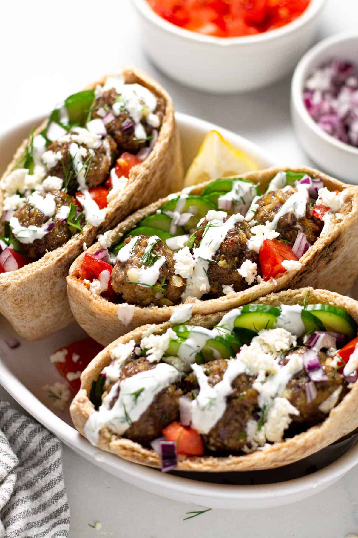Close up shot of three Greek meatball gyros with yogurt sauce and fresh dill