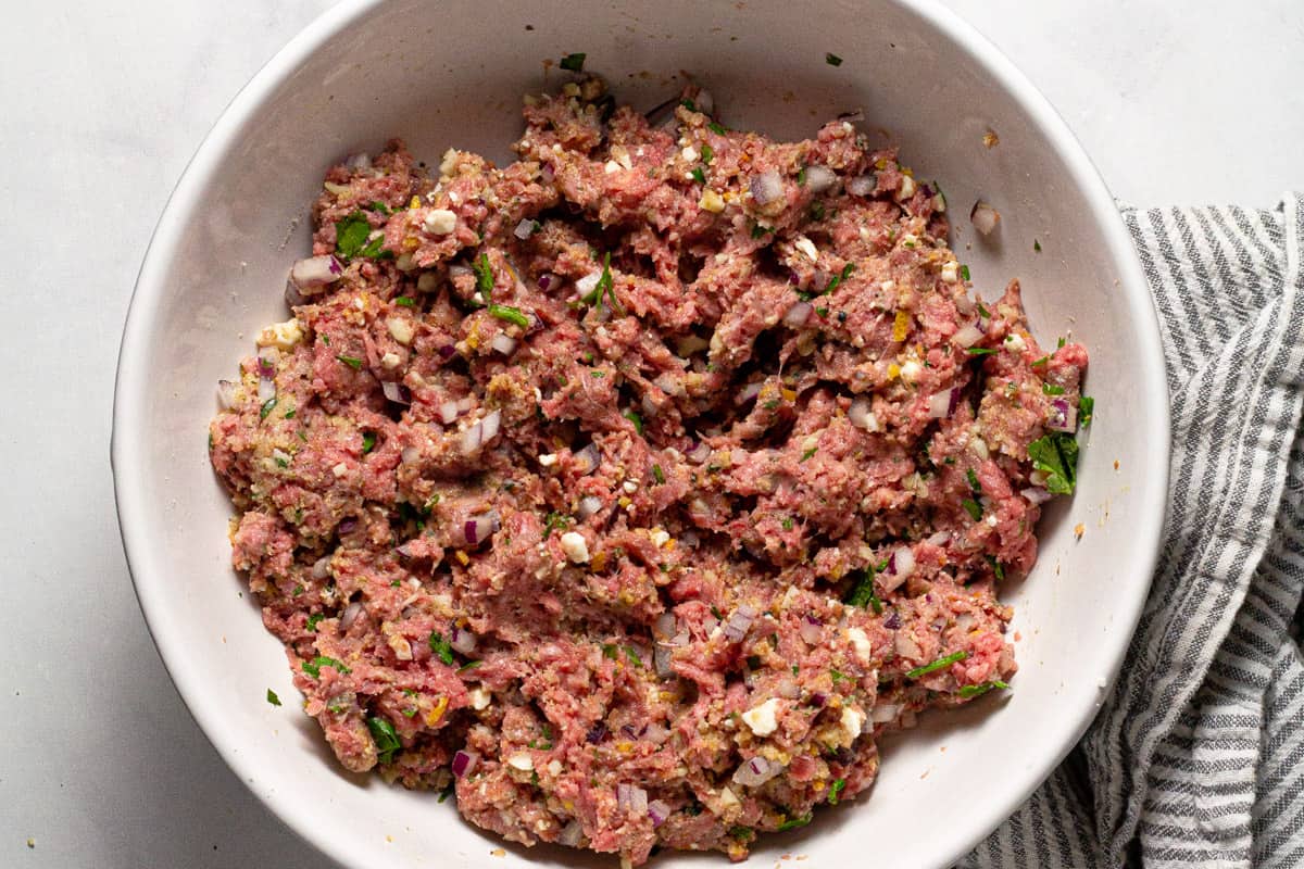 Large white bowl with ingredients to make Greek meatballs