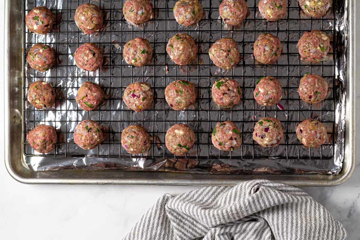 Greek meatballs on a cooling rack on a baking sheet