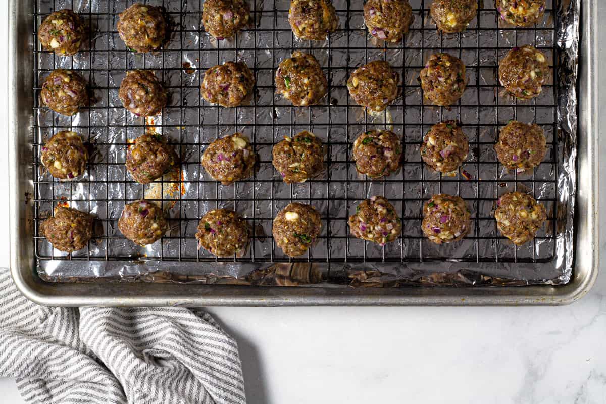 Baked Greek meatballs on a cooling rack on a baking sheet