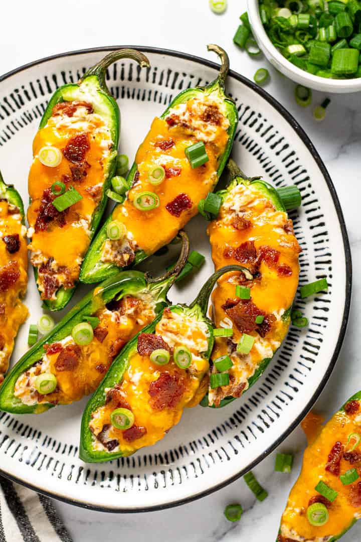 Black and white plate filled with baked jalapeno poppers garnished with green onion