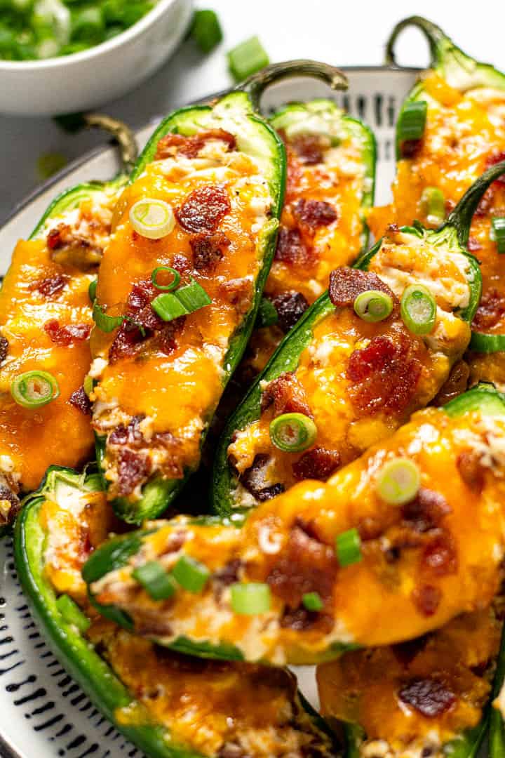 Black and white plate filled with baked jalapeno poppers garnished with green onion