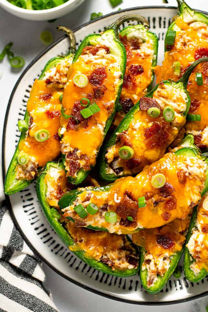 Black and white plate filled with baked jalapeno poppers garnished with green onion