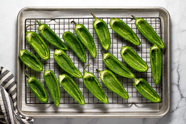 Sliced and seeded jalapeno on a parchment lined baking sheet 