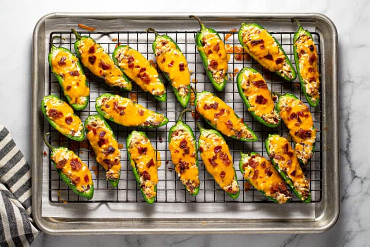 An overhead shot of a cooling rack filled with baked jalapeno poppers