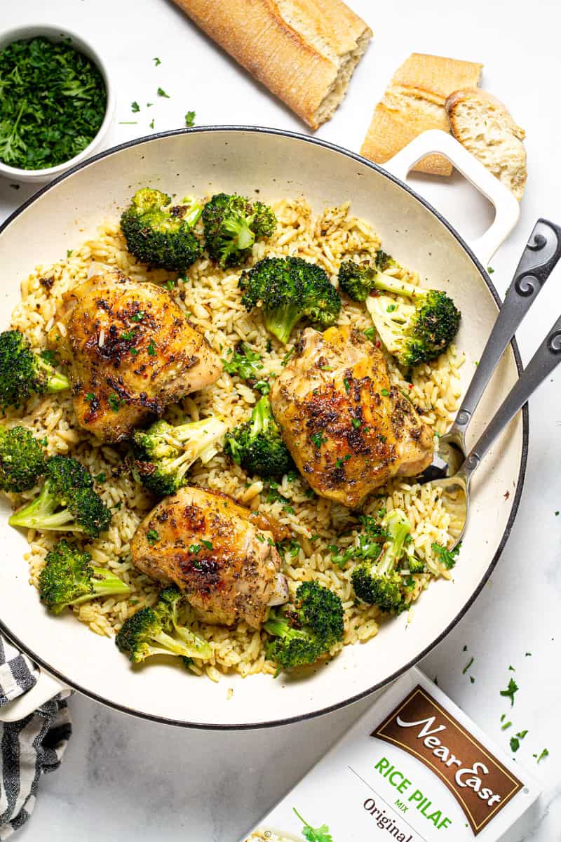 Overhead shot of a pan filled with rice pilaf broccoli and roasted chicken thighs