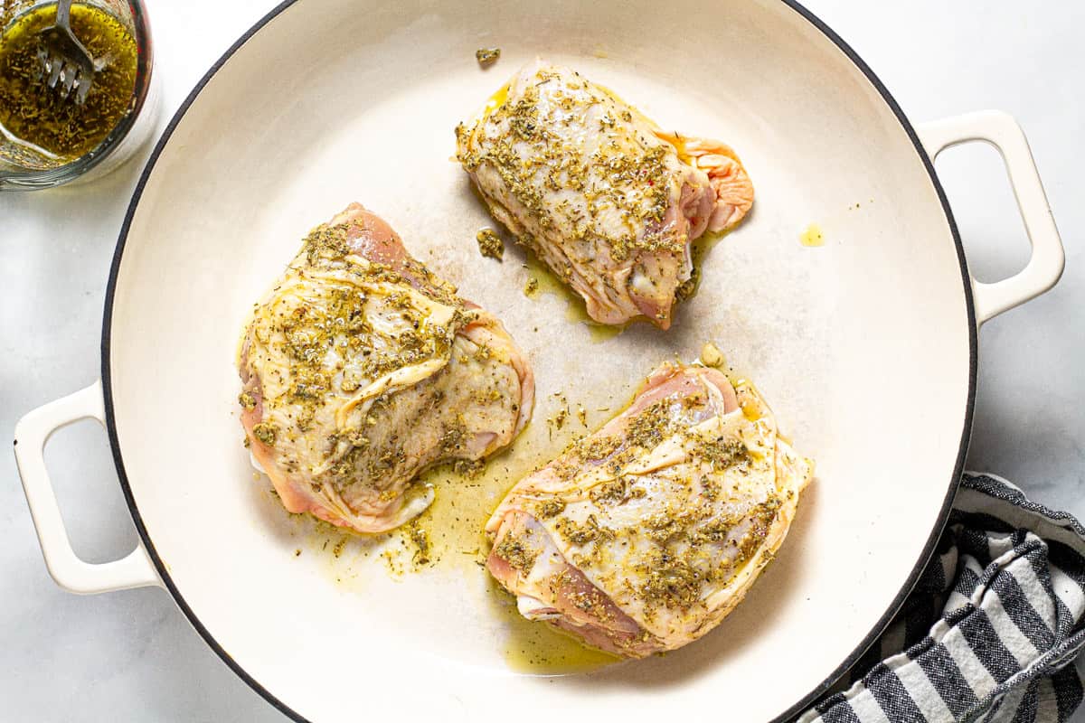 White saute pan filled with herb marinated chicken thighs