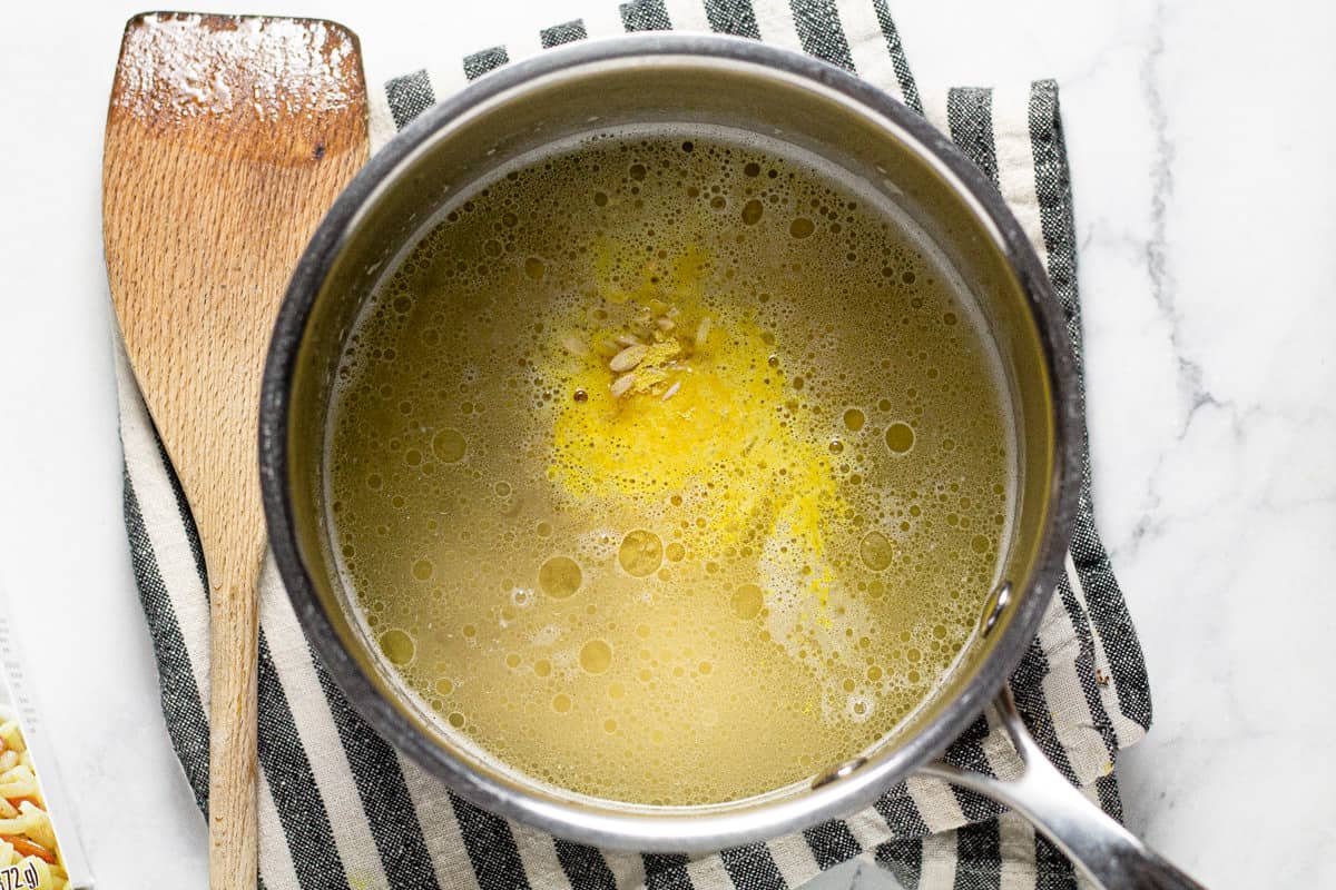 Small sauce pan filled with water butter rice and seasoning