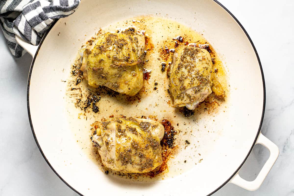 White saute pan filled with herb roasted chicken thighs