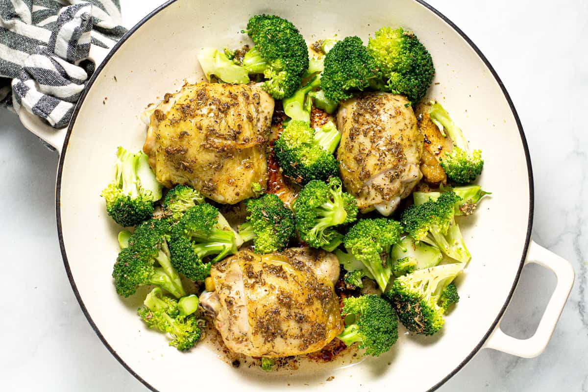 Large white pan filled with chicken thighs and broccoli