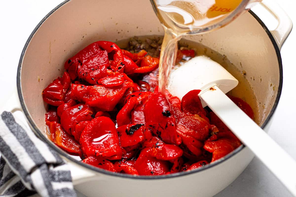 Large soup pot with ingredients to make roasted red pepper soup