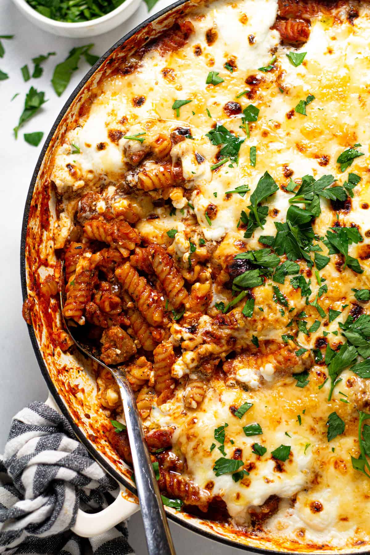 Overhead shot of a white pan filled with stove top lasagna garnished with fresh parsley