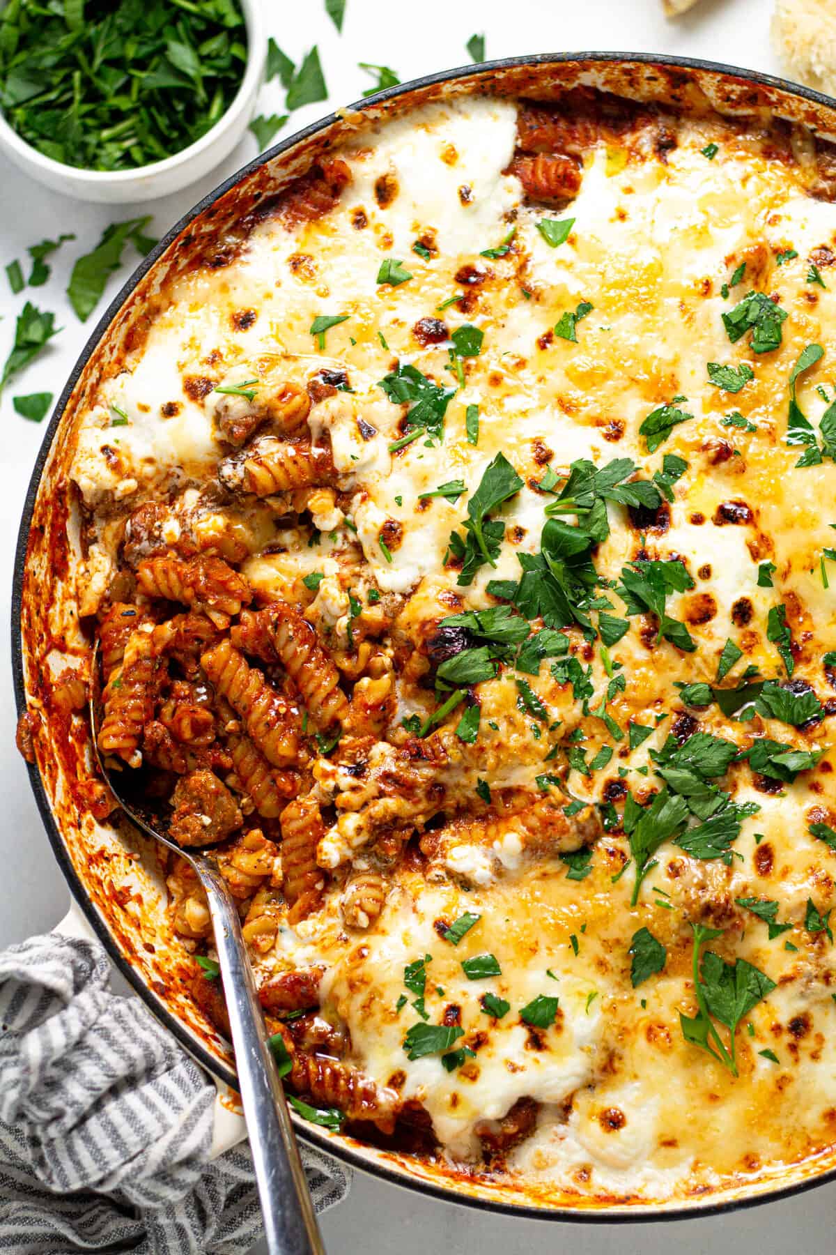 Overhead shot of a white pan filled with stove top lasagna garnished with fresh parsley