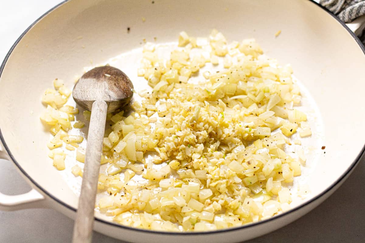 Large white pot with sauteed onion and garlic