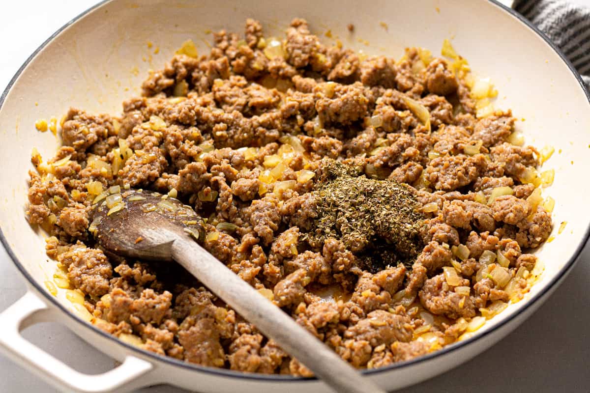 Large white pot with sauteed onion garlic and ground sausage