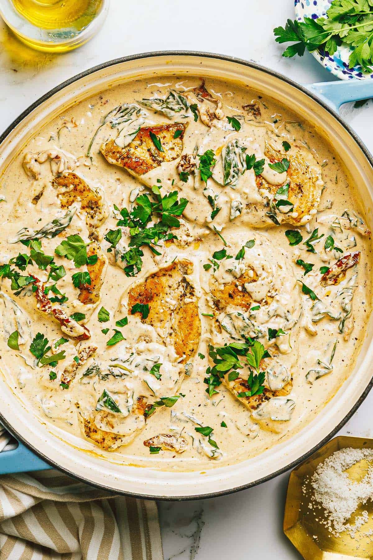 Large pan of creamy Tuscan chicken garnished with fresh parsley. 