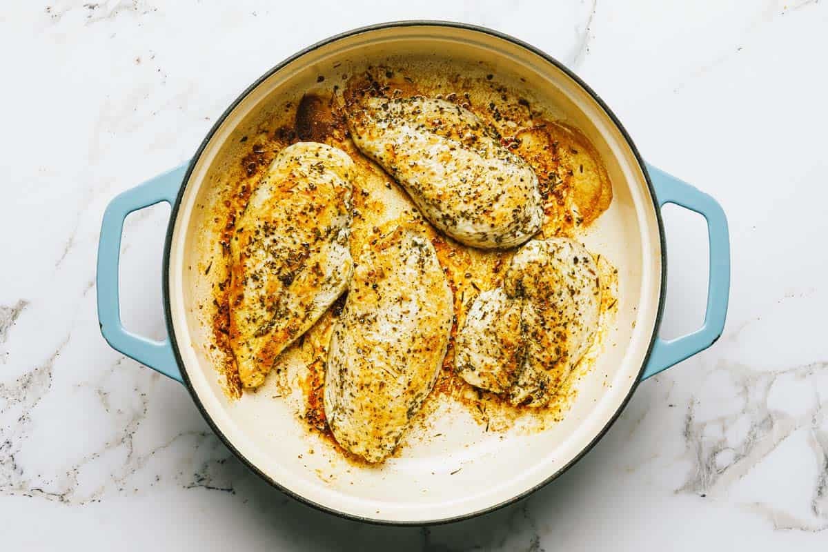 Large pan filled with sauteed chicken breast. 