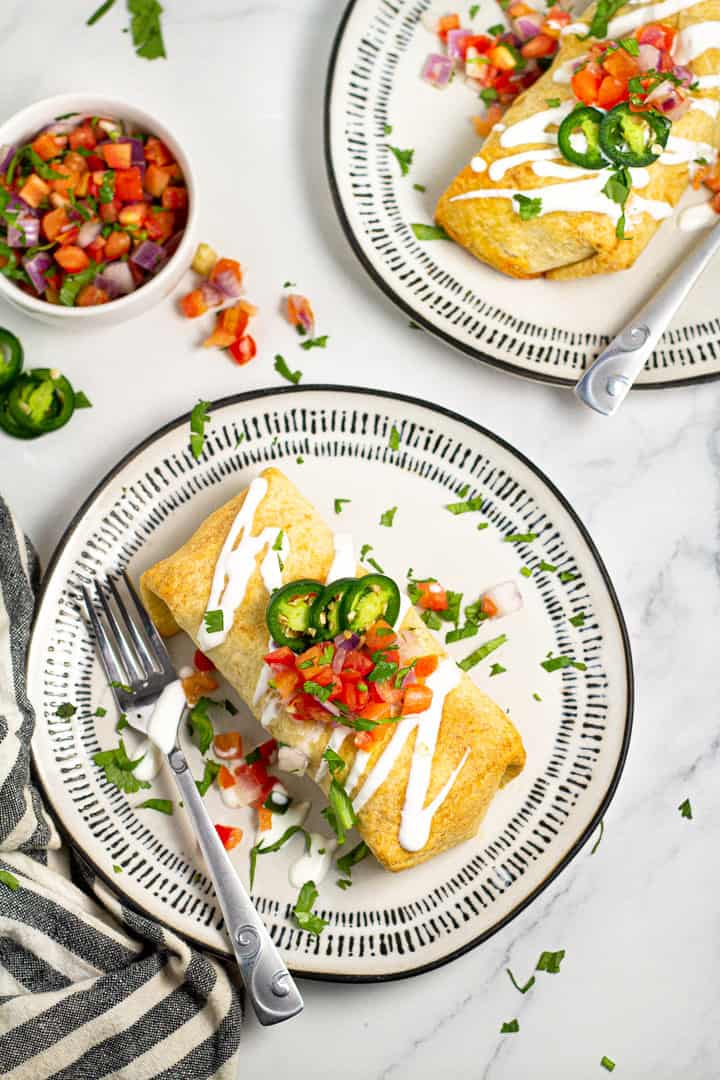 Overhead shot of a baked beef enchilada on a black and white plate