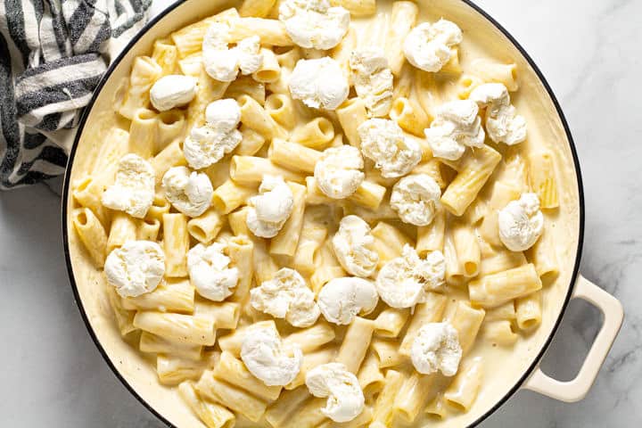 Rigatoni pasta in a creamy cheese sauce in a large white pot topped with fresh mozzarella 
