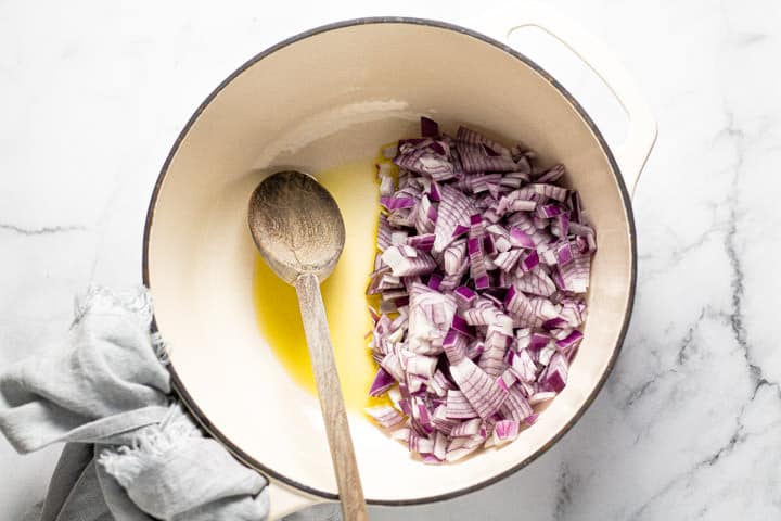 Large white pot with diced red onions and olive oil in it