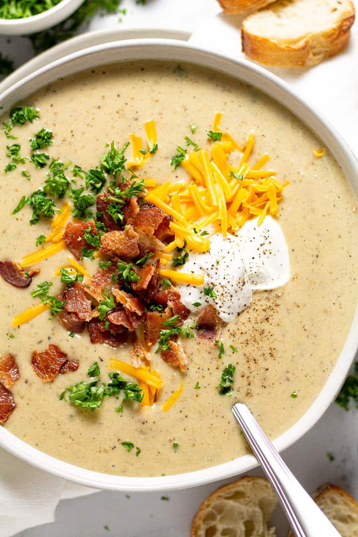 Overhead shot of a bowl of creamy potato soup garnished with cheddar cheese and bacon 