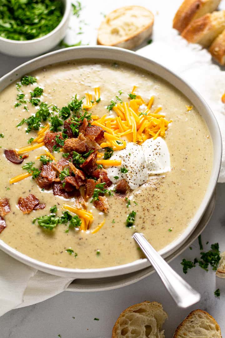 Close up shot of a bowl of creamy potato soup garnished with cheddar cheese and bacon