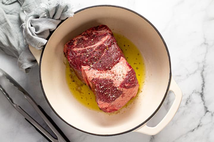 Large beef chuck roast in a pot with oil