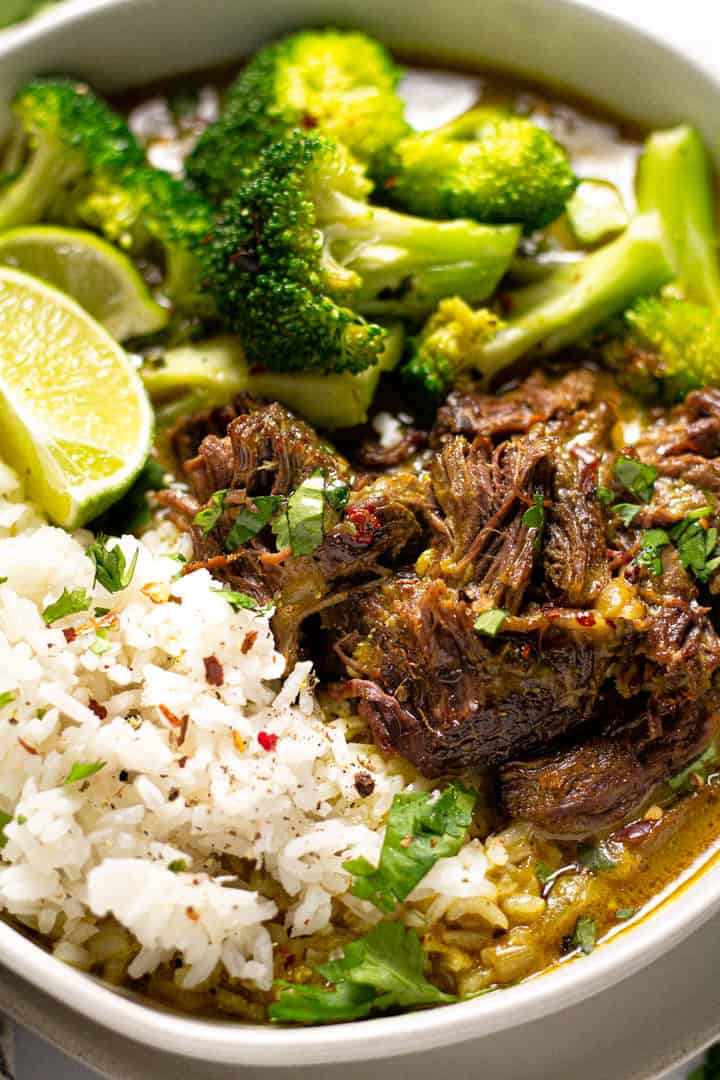Close up shot of a bowl of curried beef served over rice and garnished with cilantro