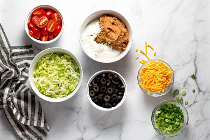 White marble counter top with ingredients to make taco dip